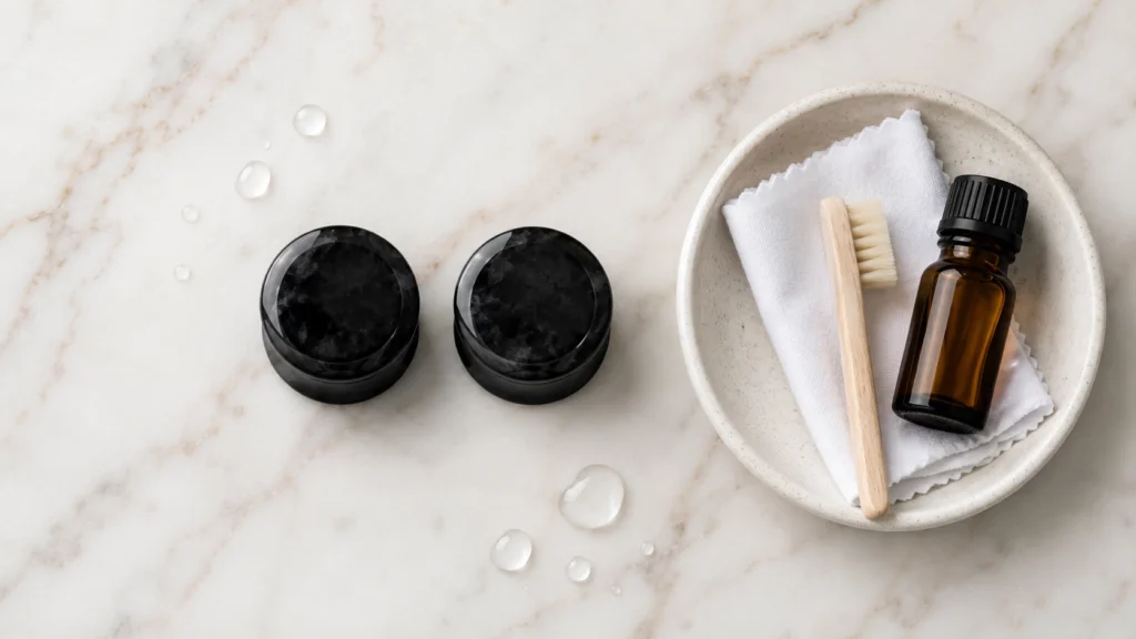 Stone-ear-plug-cleaning-kit-—-obsidian-plugs-soft-cloth-brush-and-jojoba-oil-arranged-for-care-routine